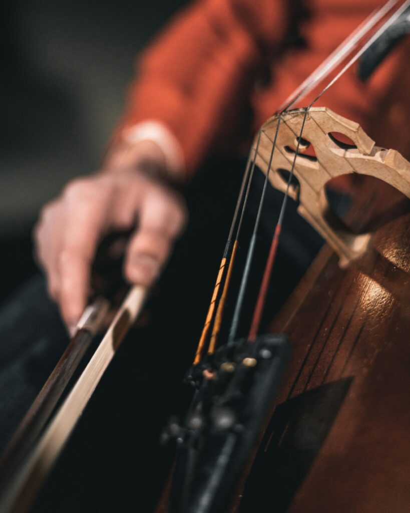An artistic close-up of a musician's hand playing cello strings, showcasing skill and craftsmanship.